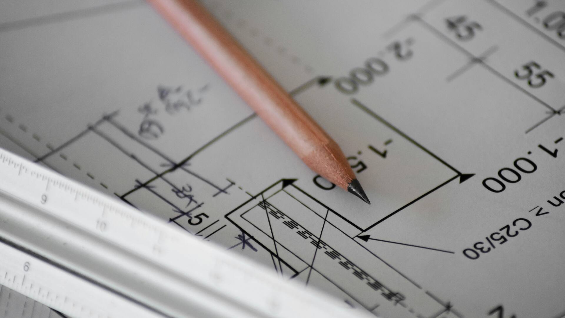 Plan technique coté, avec un crayon et une règle posés dessus.