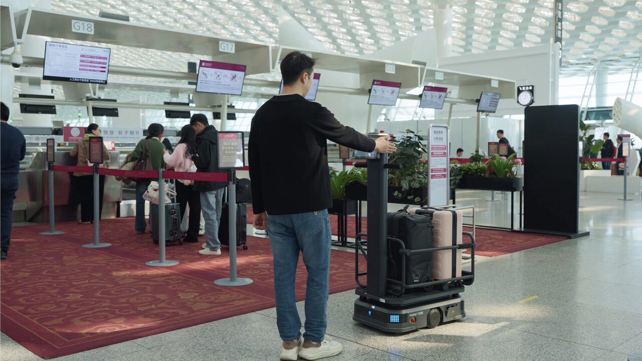 Robot de portage PUDU T300 chargé de bagages dans un hall d’enregistrement d’aéroport.