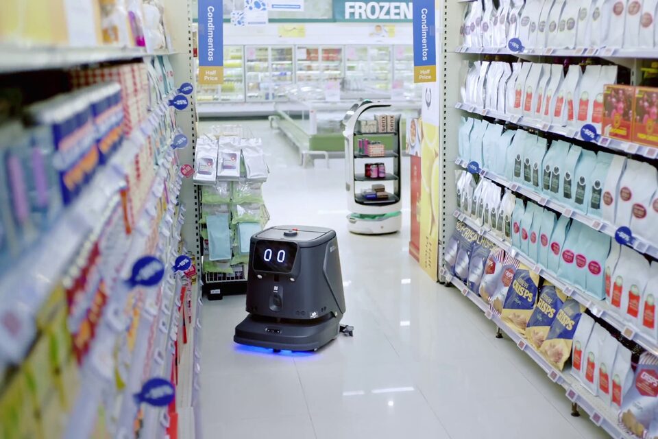 Robot autolaveur PUDU CC1 Pro traitant le sol carrelé d’une grande surface, la trace de lavage encore visible derrière lui.