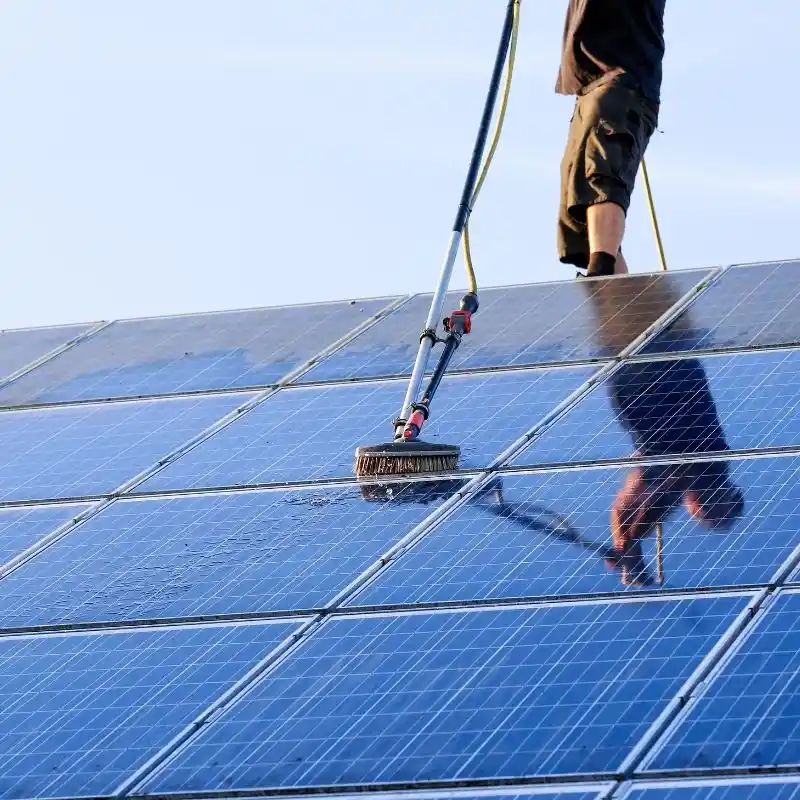 Technicien utilisant une perche télescopique pour le nettoyage extérieur de panneaux solaires et façades en Savoie.